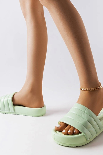 Zaļas flip-flops, kas dekorētas ar Dorene vatējumu