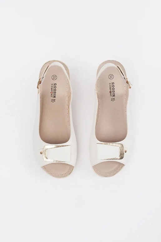 Baltas krāsas sandalī uz zema pleca...