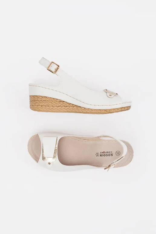 Baltas krāsas sandalī uz zema pleca...