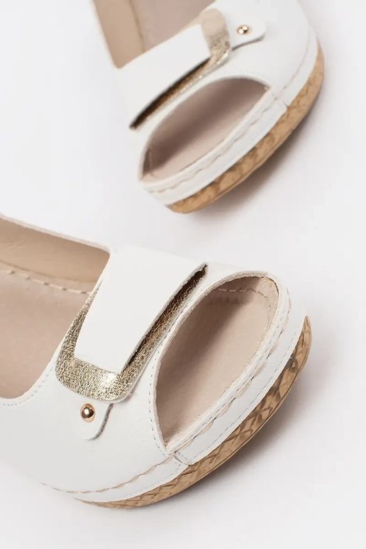 Baltas krāsas sandalī uz zema pleca...