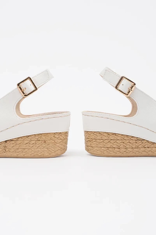 Baltas krāsas sandalī uz zema pleca...